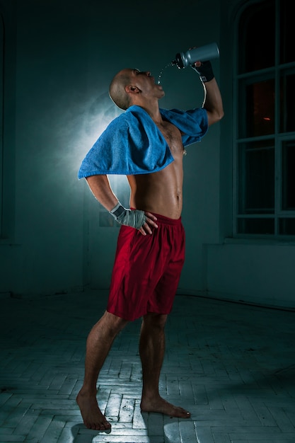 Le jeune homme kickboxing sur mur noir