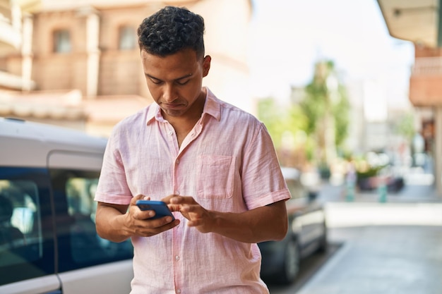 Jeune homme latin utilisant un smartphone dans la rue