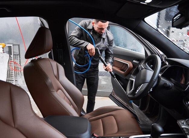 Jeune homme laver la voiture sur la station de lavage de voiture en plein air