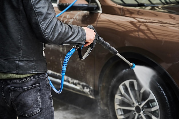 Photo gratuite jeune homme laver la voiture sur la station de lavage de voiture en plein air