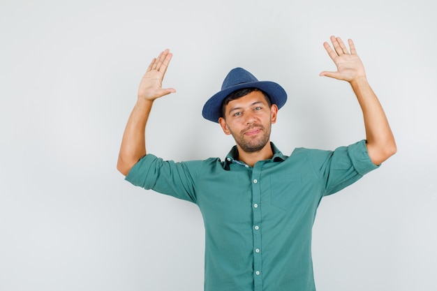 Jeune homme levant les bras en chemise, chapeau et à la joie