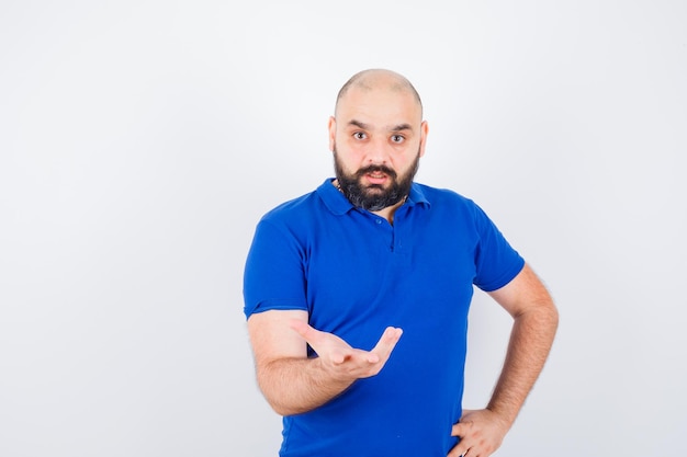 Photo gratuite jeune homme levant la main avec agressivité tout en parlant en chemise bleue et l'air nerveux. vue de face.