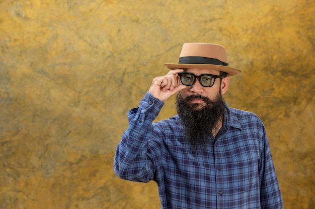 Jeune homme avec une longue barbe portant un chapeau et des lunettes