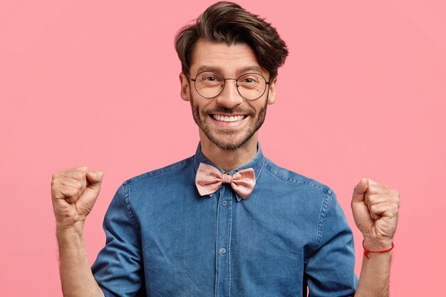 Jeune homme à lunettes rondes et noeud papillon rose