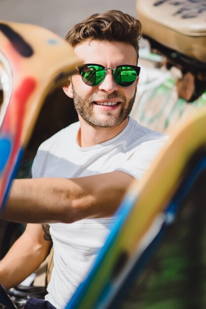 jeune homme à lunettes de soleil dans un cabriolet