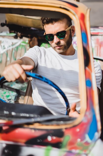 jeune homme à lunettes de soleil dans un cabriolet