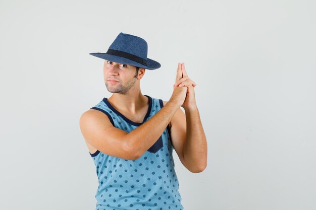 Jeune homme en maillot bleu, chapeau faisant le geste de tir et à la confiance