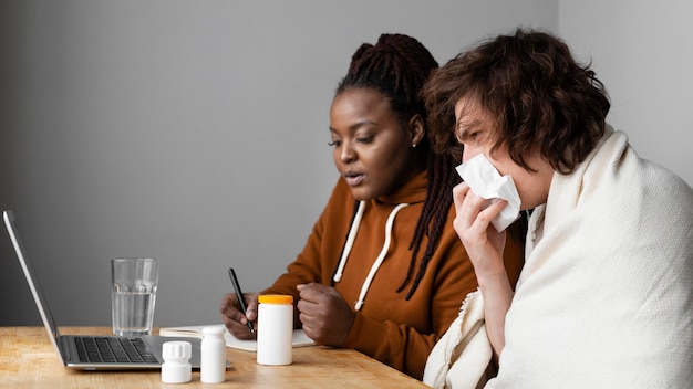 Jeune homme malade et ami ayant un appel vidéo avec un médecin