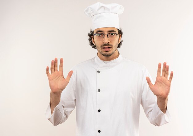 Un jeune homme malheureux cuisinier portant l'uniforme de chef et des lunettes montrant le geste d'arrêt