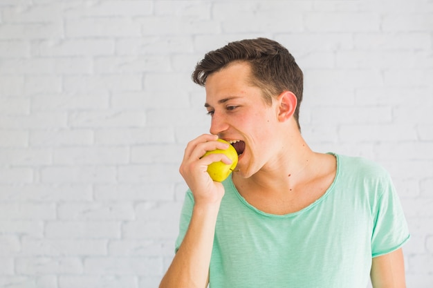 Jeune homme mangeant une pomme verte fraîche