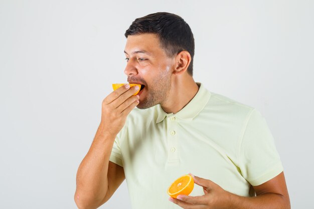 Jeune homme mangeant une des tranches d'orange en vue de face de t-shirt.