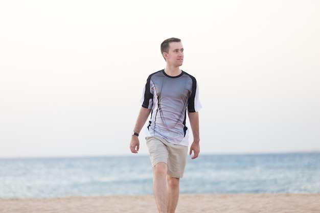 Jeune homme marchant sur la plage