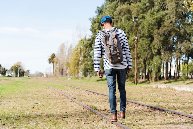 Jeune homme marchant sur des rails dans le parc