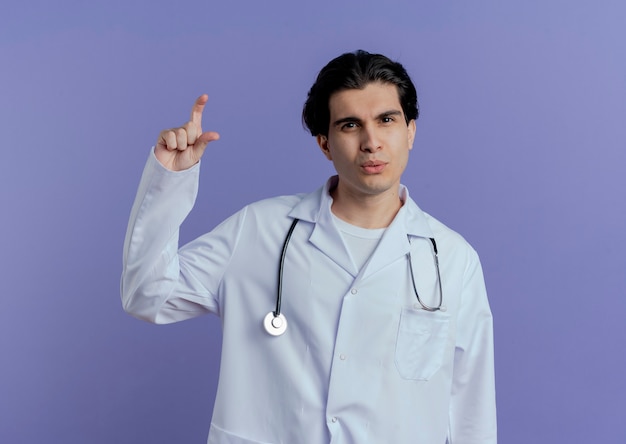 Photo gratuite jeune homme médecin portant une robe médicale et un stéthoscope faisant un geste de petite quantité isolé sur un mur violet avec espace de copie