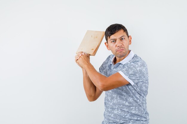 Jeune homme menaçant de planche à découper en t-shirt et à la colère