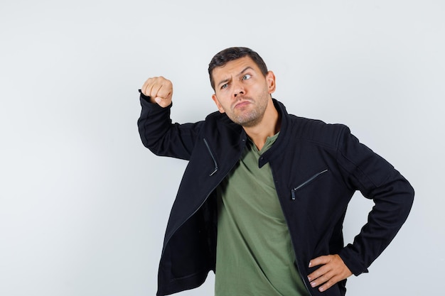 Photo gratuite jeune homme menaçant avec le poing en t-shirt, veste et l'air pensif, vue de face.