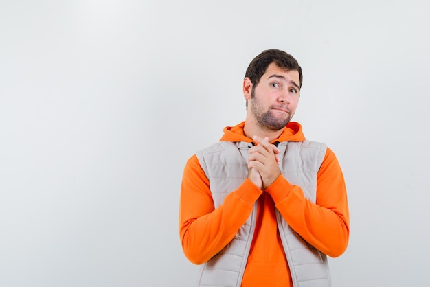 Le jeune homme mendie en joignant les mains sur fond blanc