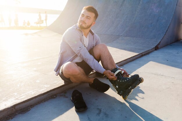 Jeune homme, mettre, sur, rollerskates, dans, skate park