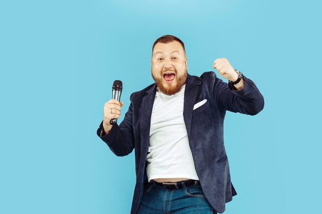 Jeune homme avec microphone sur bleu, concept de premier plan