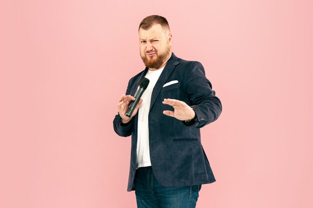 Jeune homme avec microphone sur espace rose, menant avec microphone