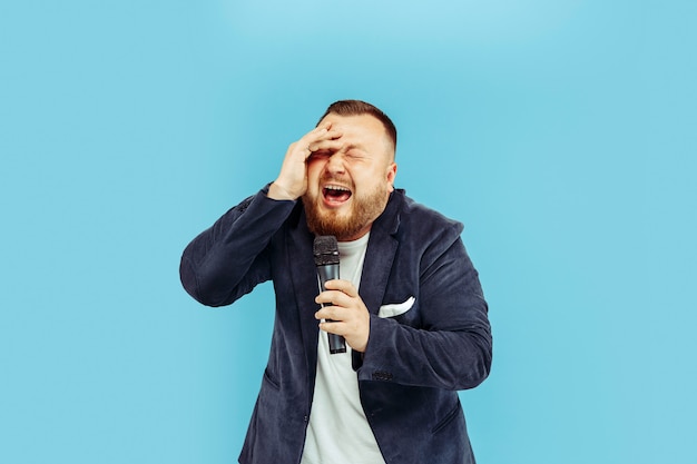 Photo gratuite jeune homme avec microphone sur mur bleu