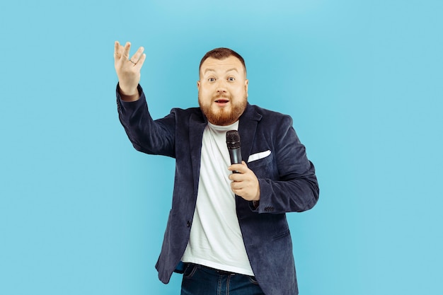 Jeune homme avec microphone sur studio bleu, concept de premier plan