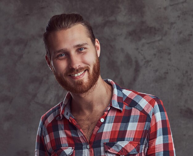 Un jeune homme modèle rousse beau et souriant dans une chemise en flanelle sur fond gris.