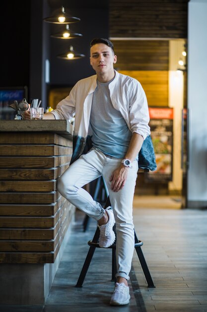 Jeune homme moderne avec un verre de whisky au bar comptoir