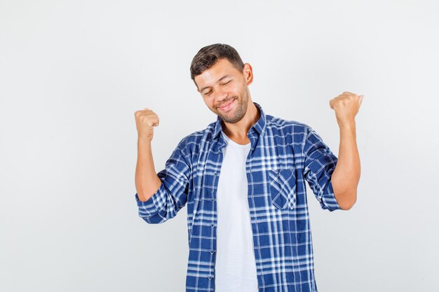 Jeune homme montrant le geste du gagnant en chemise et l'air heureux. vue de face.