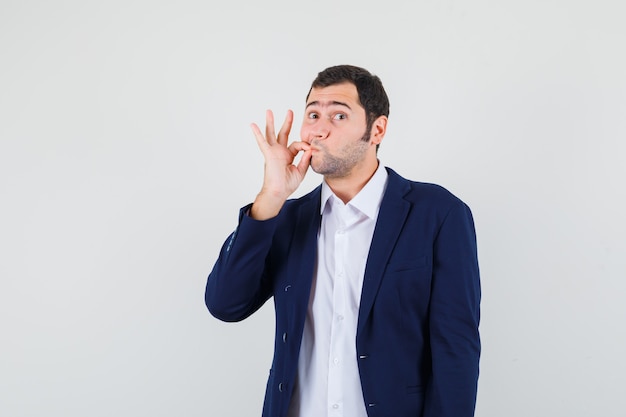 Photo gratuite jeune homme montrant le geste de fermeture éclair en chemise