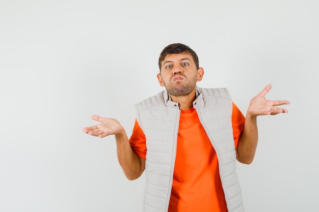 Jeune homme montrant un geste impuissant en soufflant les joues en t-shirt, veste