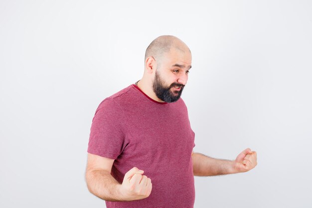 Jeune homme montrant un geste de réussite en t-shirt rose et semblant puissant. .