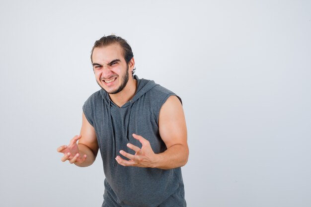 Jeune homme montrant des griffes imitant le chat en t-shirt à capuche et à la folle, vue de face.