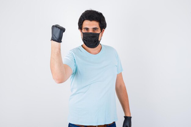 Jeune homme montrant le poing levé en t-shirt et à la rancune. vue de face.