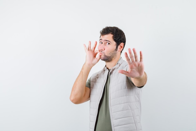 Jeune homme montrant un signe de la main OK et faisant un signe de la main d'arrêt sur fond blanc