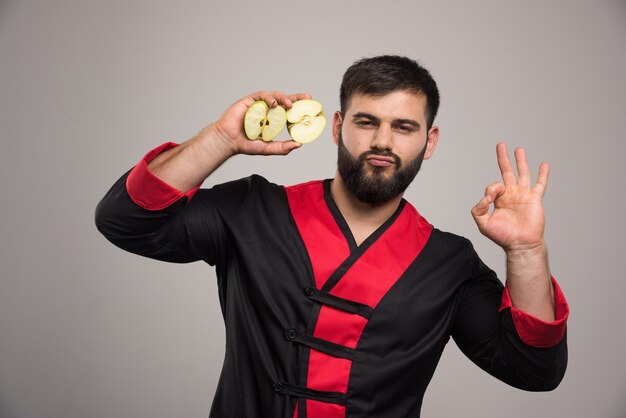 Jeune homme montrant une tranche de pomme fraîche.