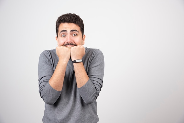 Jeune homme avec moustache peur de mettre les mains à la bouche.