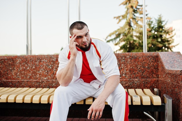 Jeune Homme Musclé Barbu Brutal Portant Un Costume De Sport Blanc Avec Une Chemise Rouge