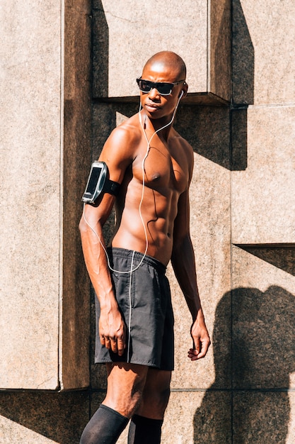 Un jeune homme musclé, écoutant de la musique sur un téléphone portable dans l&#39;étui à brassard, regardant au loin