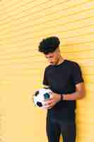 Photo gratuite jeune homme noir avec ballon de foot en baissant la tête