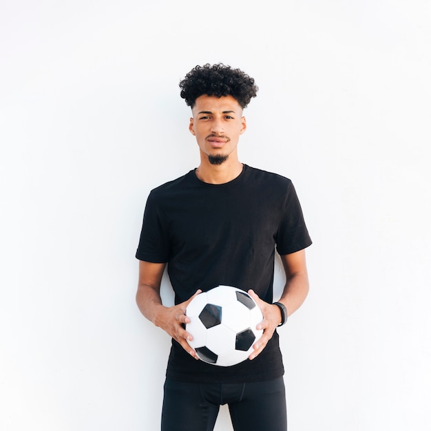 Jeune homme noir avec ballon en regardant la caméra