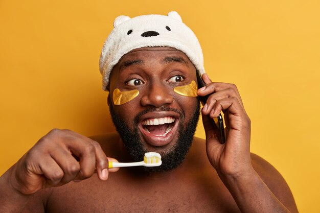 Jeune homme noir se brosse les dents, parle sur téléphone intelligent, applique des patchs de collagène