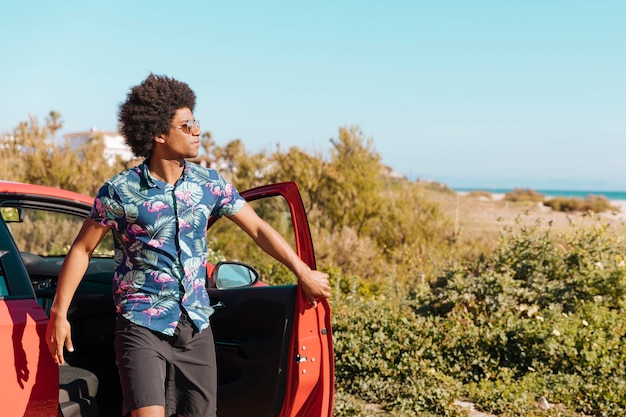 Photo gratuite jeune homme noir sortant de la voiture sur la nature