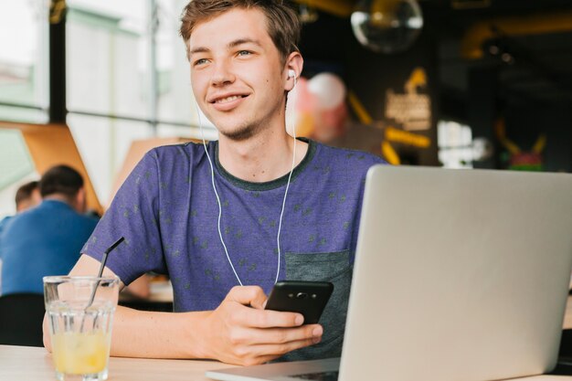 Jeune homme avec un ordinateur portable et des écouteurs