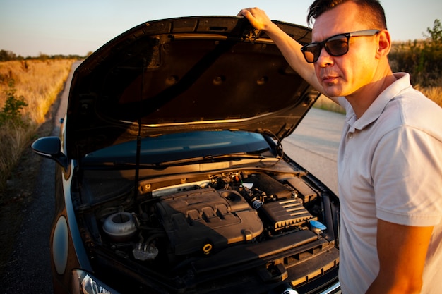 Jeune homme ouvrant le capot de la voiture