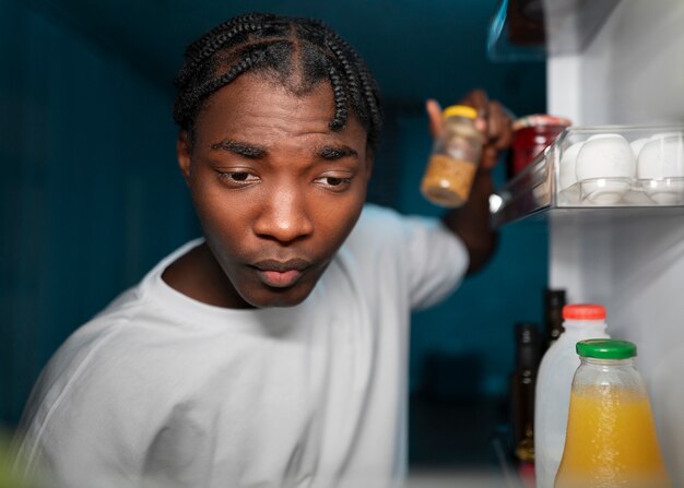 Jeune homme ouvrant le réfrigérateur à la maison pour une collation au milieu de la nuit
