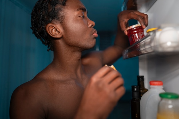 Jeune homme ouvrant le réfrigérateur à la maison pour une collation au milieu de la nuit