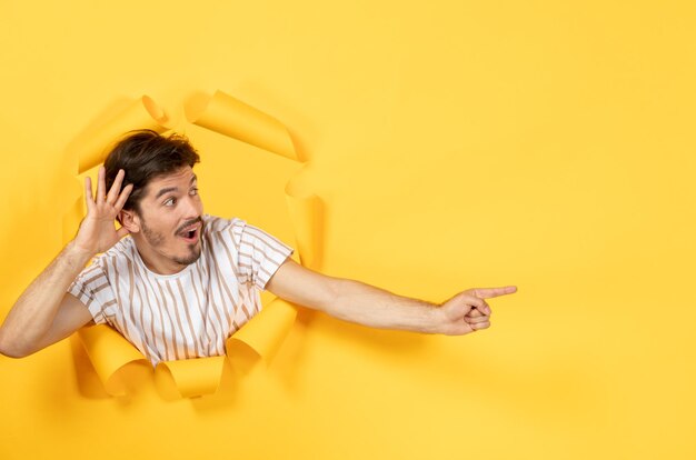 Jeune homme sur papier jaune déchiré surface vente intérieur type facial