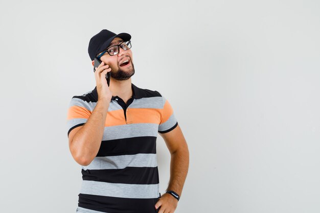 Jeune homme parlant au téléphone mobile en t-shirt, casquette et à la joyeuse