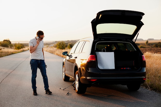 Jeune homme parlant au téléphone près d'une voiture